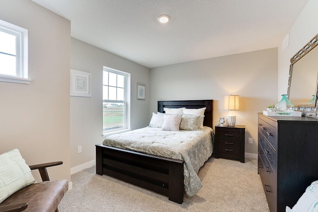 bedroom featuring baseboards, a textured ceiling, and light colored carpet