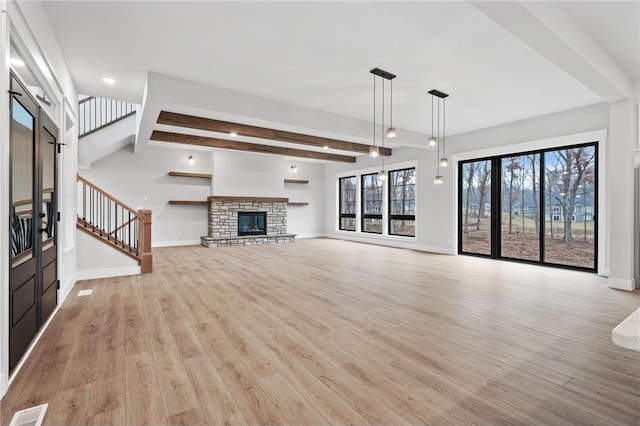 unfurnished living room with a stone fireplace, beamed ceiling, and light wood-type flooring