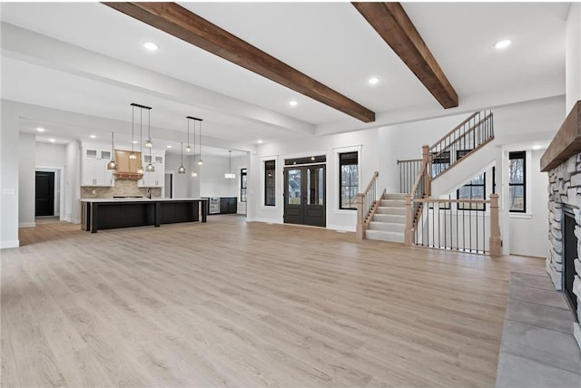 unfurnished living room featuring a healthy amount of sunlight, a stone fireplace, and light wood-type flooring