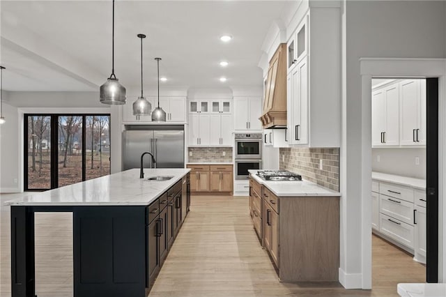 kitchen with a large island with sink, white cabinetry, decorative light fixtures, and appliances with stainless steel finishes