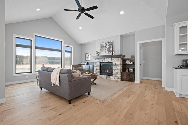 living room featuring a fireplace, high vaulted ceiling, light hardwood / wood-style flooring, and ceiling fan