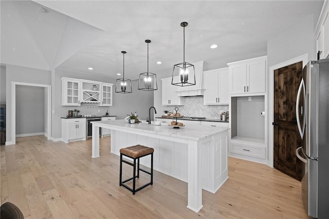 kitchen with a center island with sink, white cabinets, beverage cooler, and appliances with stainless steel finishes