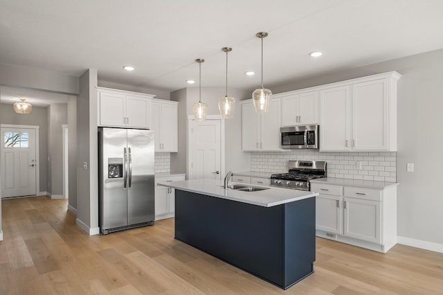 kitchen with white cabinetry, sink, light hardwood / wood-style flooring, pendant lighting, and appliances with stainless steel finishes