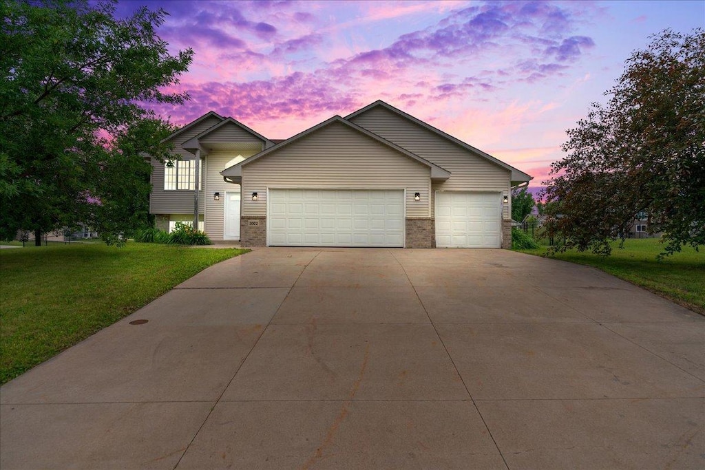 view of front of house featuring a garage, driveway, brick siding, and a front lawn