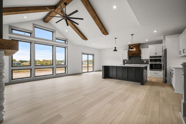 kitchen featuring white cabinets, hanging light fixtures, light hardwood / wood-style flooring, an island with sink, and stainless steel appliances