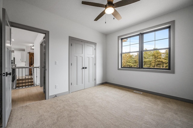 unfurnished bedroom with ceiling fan, a closet, light carpet, and a textured ceiling