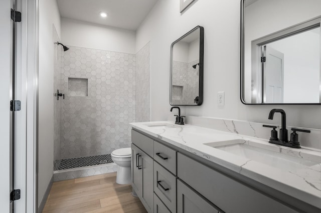 bathroom featuring a tile shower, toilet, vanity, and hardwood / wood-style flooring