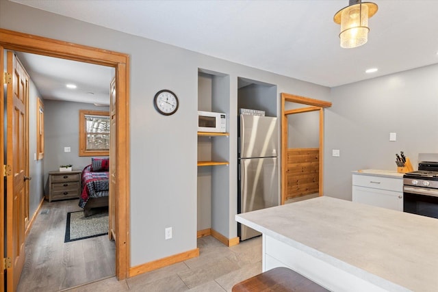 kitchen featuring white cabinetry, light hardwood / wood-style floors, decorative light fixtures, and appliances with stainless steel finishes