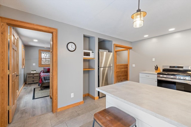 kitchen featuring appliances with stainless steel finishes, a breakfast bar, decorative light fixtures, light hardwood / wood-style flooring, and white cabinetry