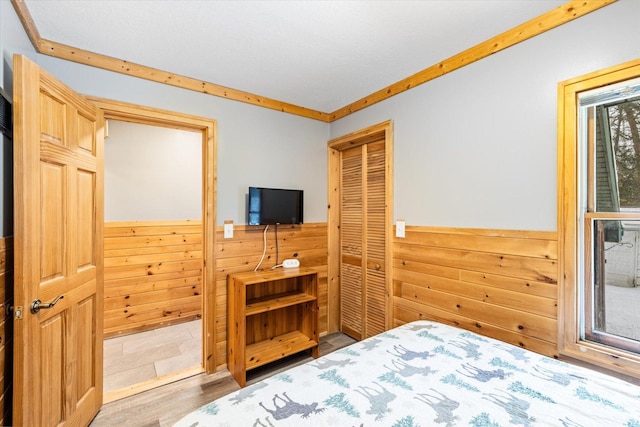 bedroom with hardwood / wood-style flooring, wood walls, and a closet