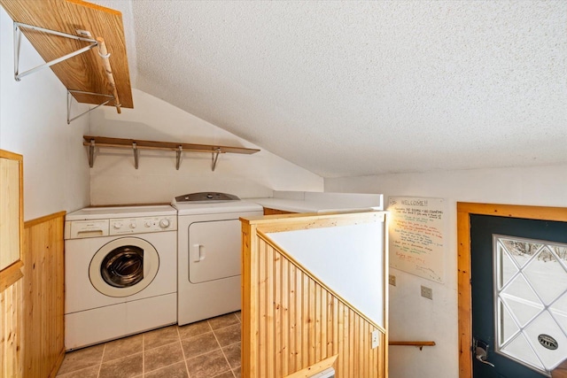 clothes washing area featuring a textured ceiling, washer and clothes dryer, and wooden walls