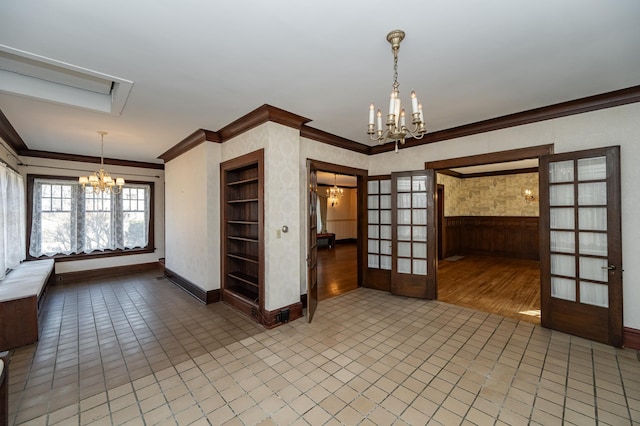 empty room featuring french doors, baseboards, a chandelier, and crown molding