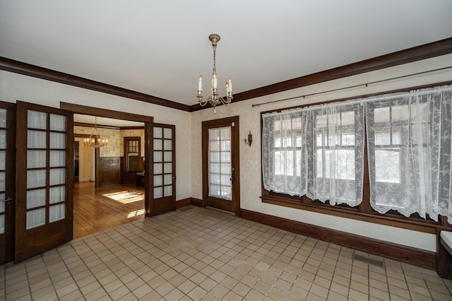 spare room featuring an inviting chandelier, french doors, baseboards, and ornamental molding