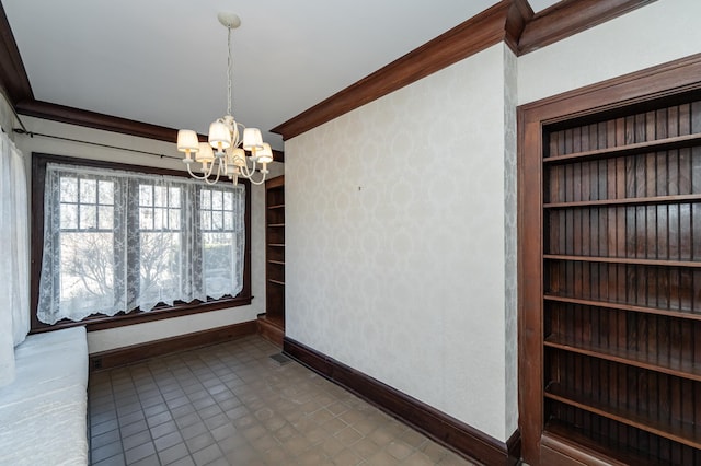 unfurnished dining area with built in features, baseboards, crown molding, and an inviting chandelier