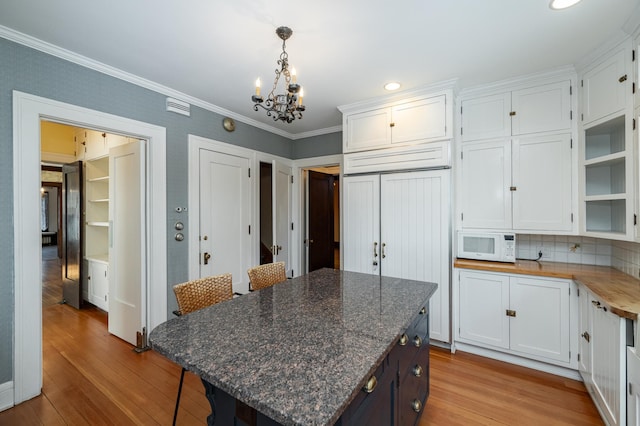 kitchen with white cabinetry, light wood-style flooring, white microwave, and ornamental molding