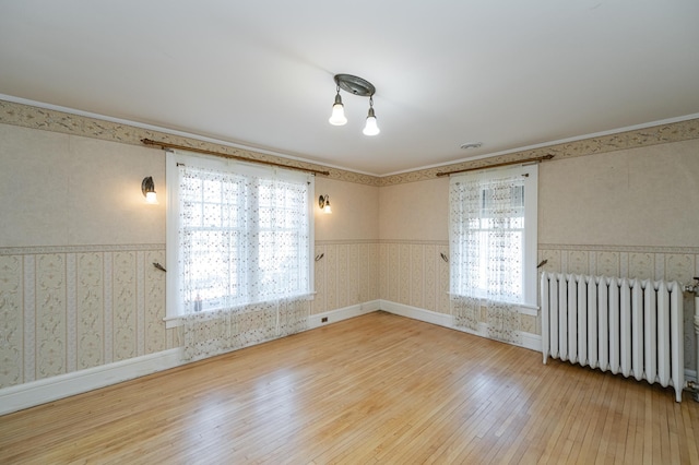 spare room with plenty of natural light, radiator, hardwood / wood-style flooring, and wallpapered walls