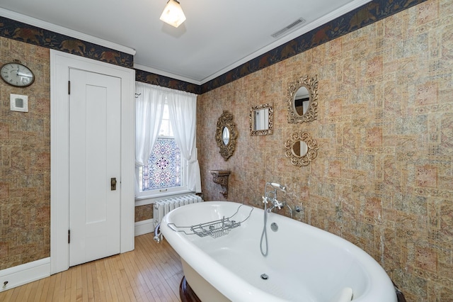 full bathroom featuring visible vents, radiator, crown molding, baseboards, and a freestanding bath