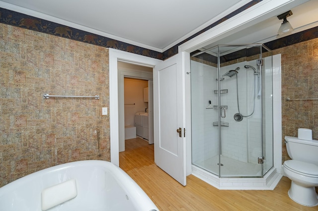 bathroom featuring a shower stall, toilet, tile walls, and washer and clothes dryer