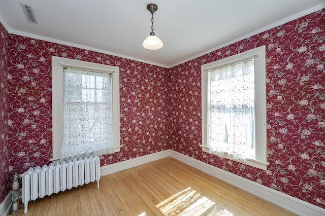 spare room featuring a wealth of natural light, visible vents, wood-type flooring, and radiator