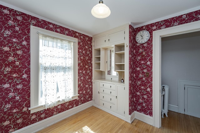 interior space featuring wallpapered walls, light wood-type flooring, and baseboards