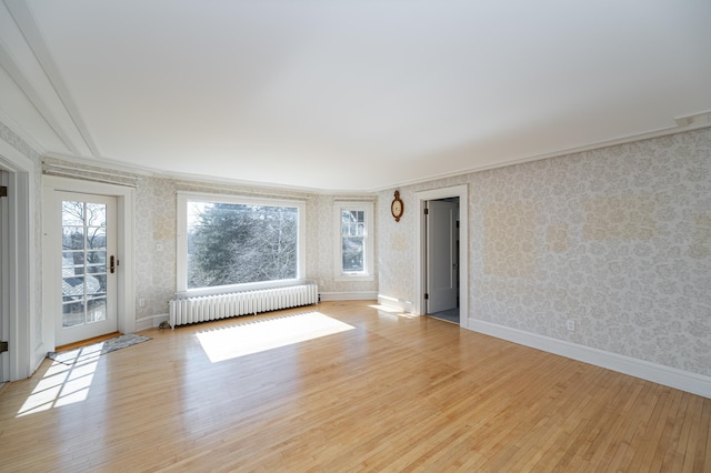 empty room featuring visible vents, wood finished floors, radiator heating unit, wallpapered walls, and baseboards