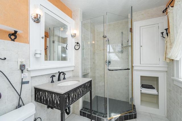 full bath featuring toilet, a stall shower, tile walls, and a sink