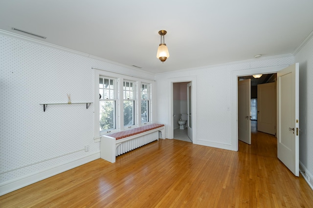 empty room with ornamental molding, radiator heating unit, and wallpapered walls