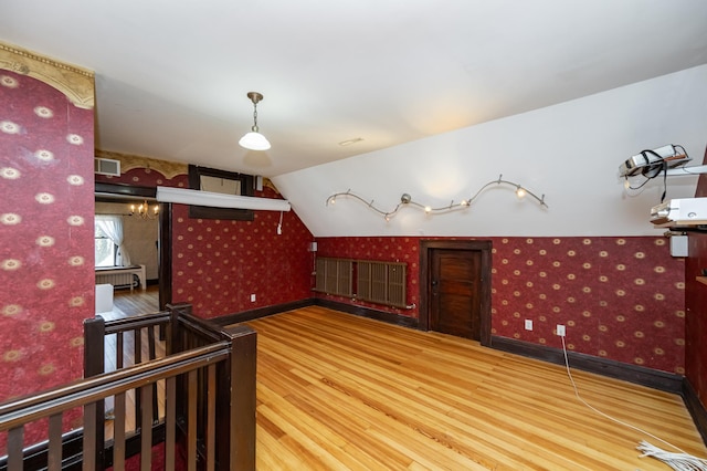 bonus room featuring visible vents, wood finished floors, wallpapered walls, baseboards, and vaulted ceiling