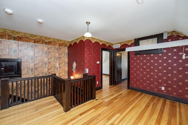 kitchen featuring visible vents, wallpapered walls, baseboards, and wood finished floors