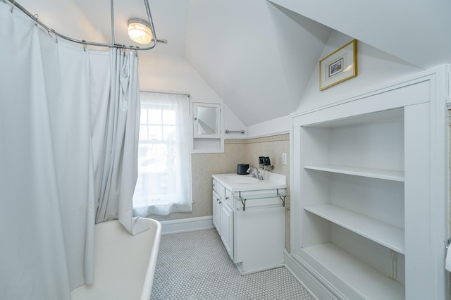 interior space with vanity, lofted ceiling, and baseboards