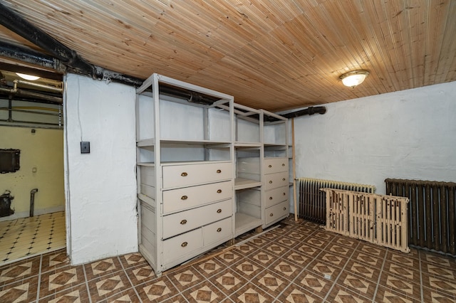 below grade area featuring tile patterned floors, wood ceiling, and radiator heating unit