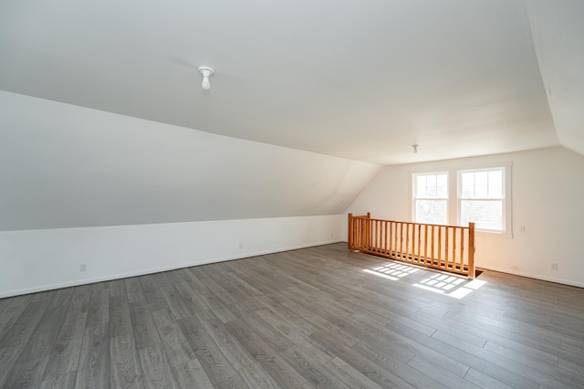 additional living space featuring dark wood-type flooring, baseboards, and lofted ceiling