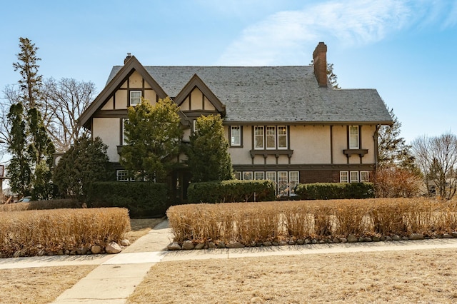 tudor-style house with stucco siding and a chimney