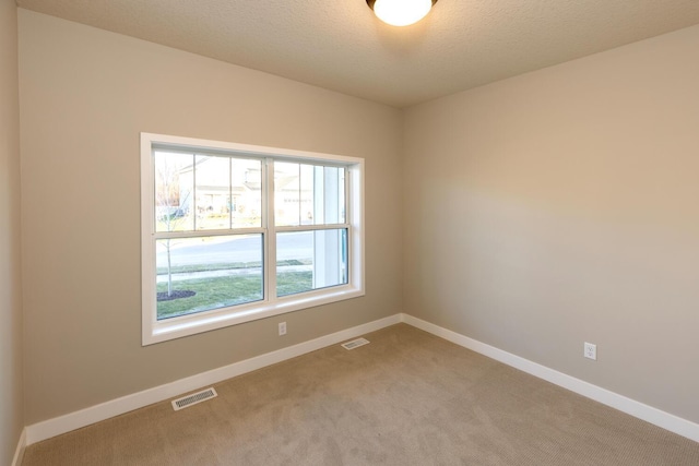 carpeted empty room featuring a textured ceiling