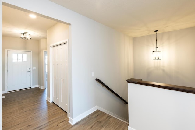 staircase with hardwood / wood-style floors and a notable chandelier