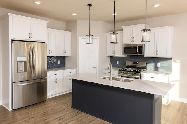 kitchen featuring backsplash, white cabinetry, stainless steel appliances, and decorative light fixtures