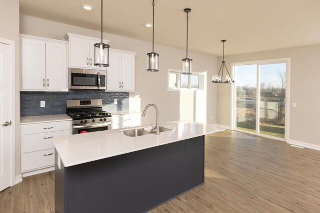 kitchen featuring sink, decorative light fixtures, a center island with sink, white cabinets, and appliances with stainless steel finishes