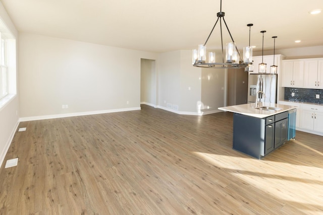 kitchen with white cabinets, pendant lighting, light hardwood / wood-style floors, and stainless steel fridge