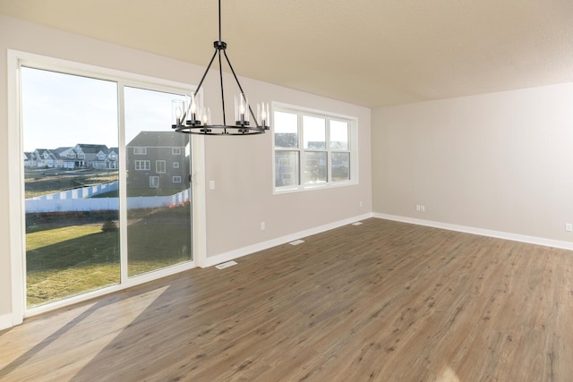 unfurnished dining area featuring hardwood / wood-style flooring, an inviting chandelier, and a water view