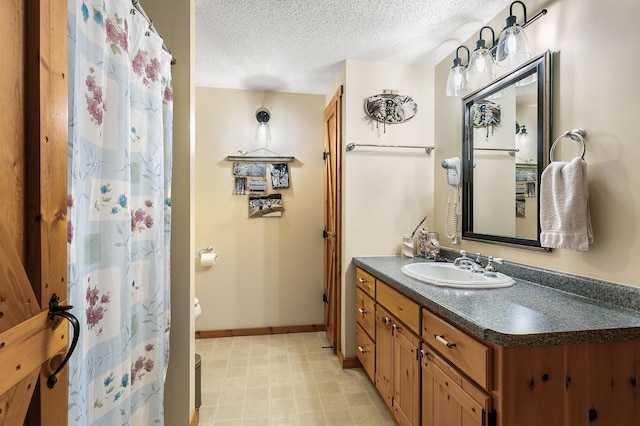 bathroom featuring baseboards, a textured ceiling, vanity, and toilet