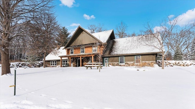 snow covered property featuring stone siding