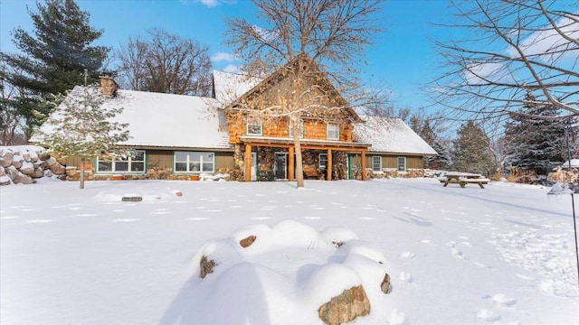 snow covered back of property with a chimney