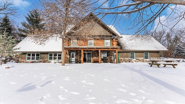 snow covered property with stone siding