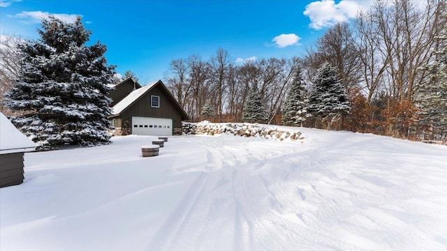 snowy yard featuring a garage and an outdoor structure