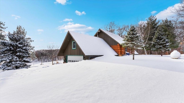 snow covered property featuring log siding and a detached garage