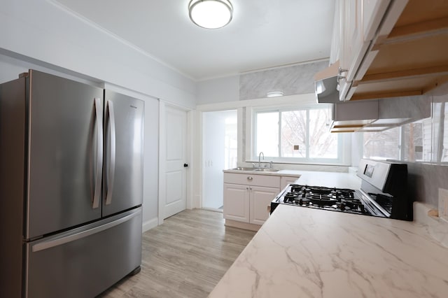 kitchen featuring light stone countertops, stainless steel fridge, sink, white cabinets, and range