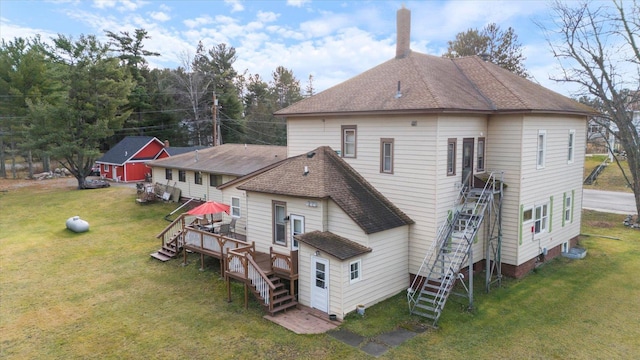 rear view of house featuring a lawn and a deck