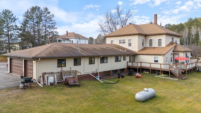 back of house with a lawn, a garage, and a deck