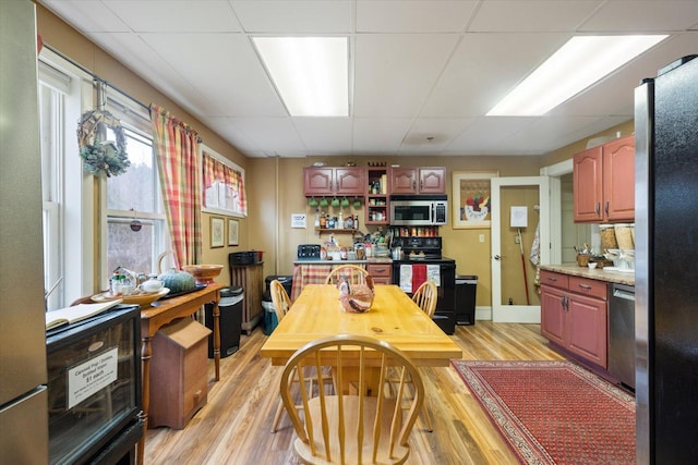 dining space featuring a drop ceiling and light wood-type flooring