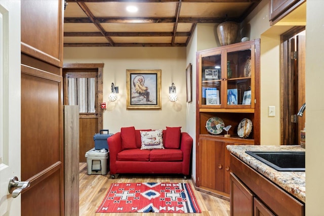 interior space with beam ceiling, sink, and light wood-type flooring